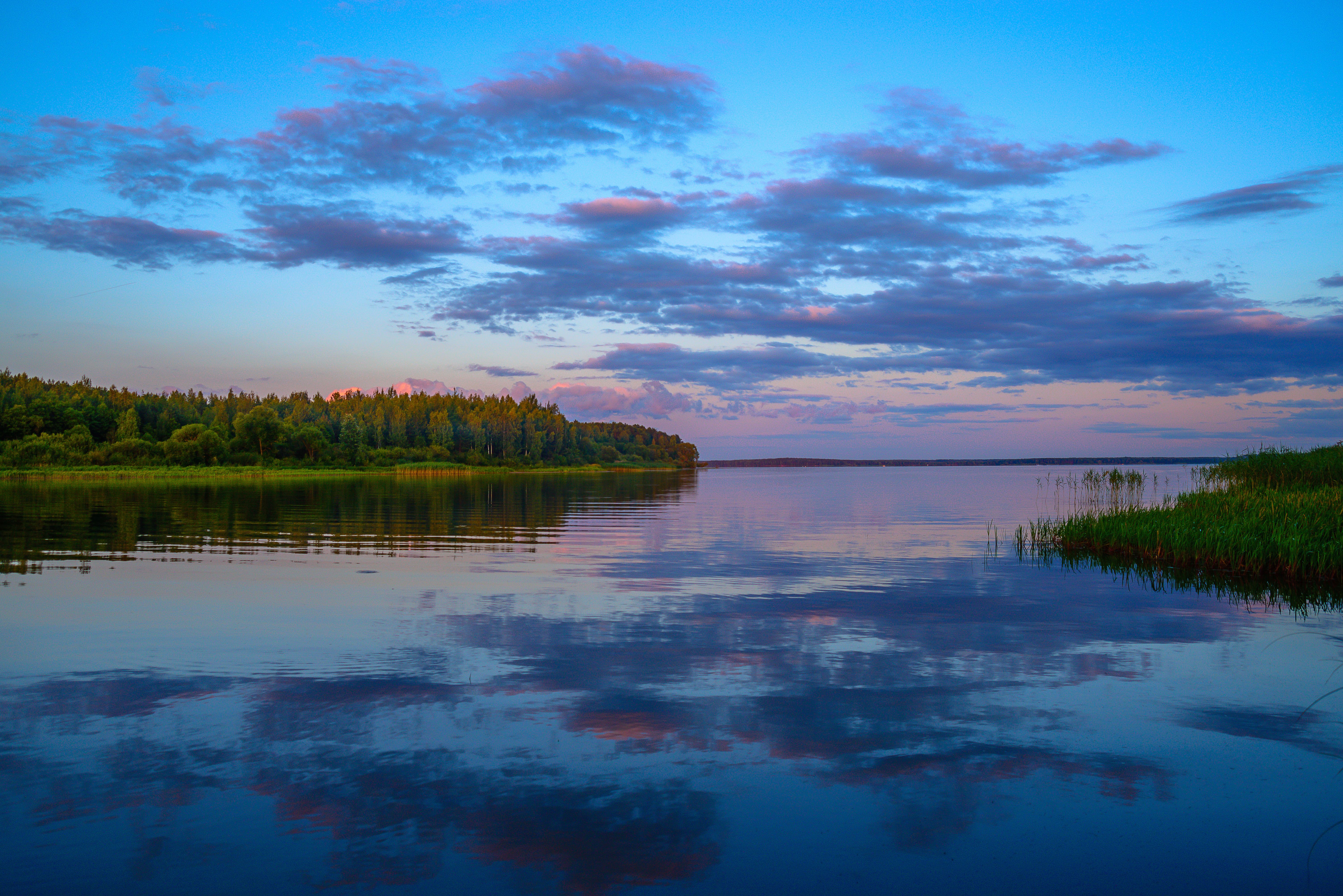 Serene sunset over Vileyka Reservoir in Belarus with vibrant clouds reflecting on calm waters.