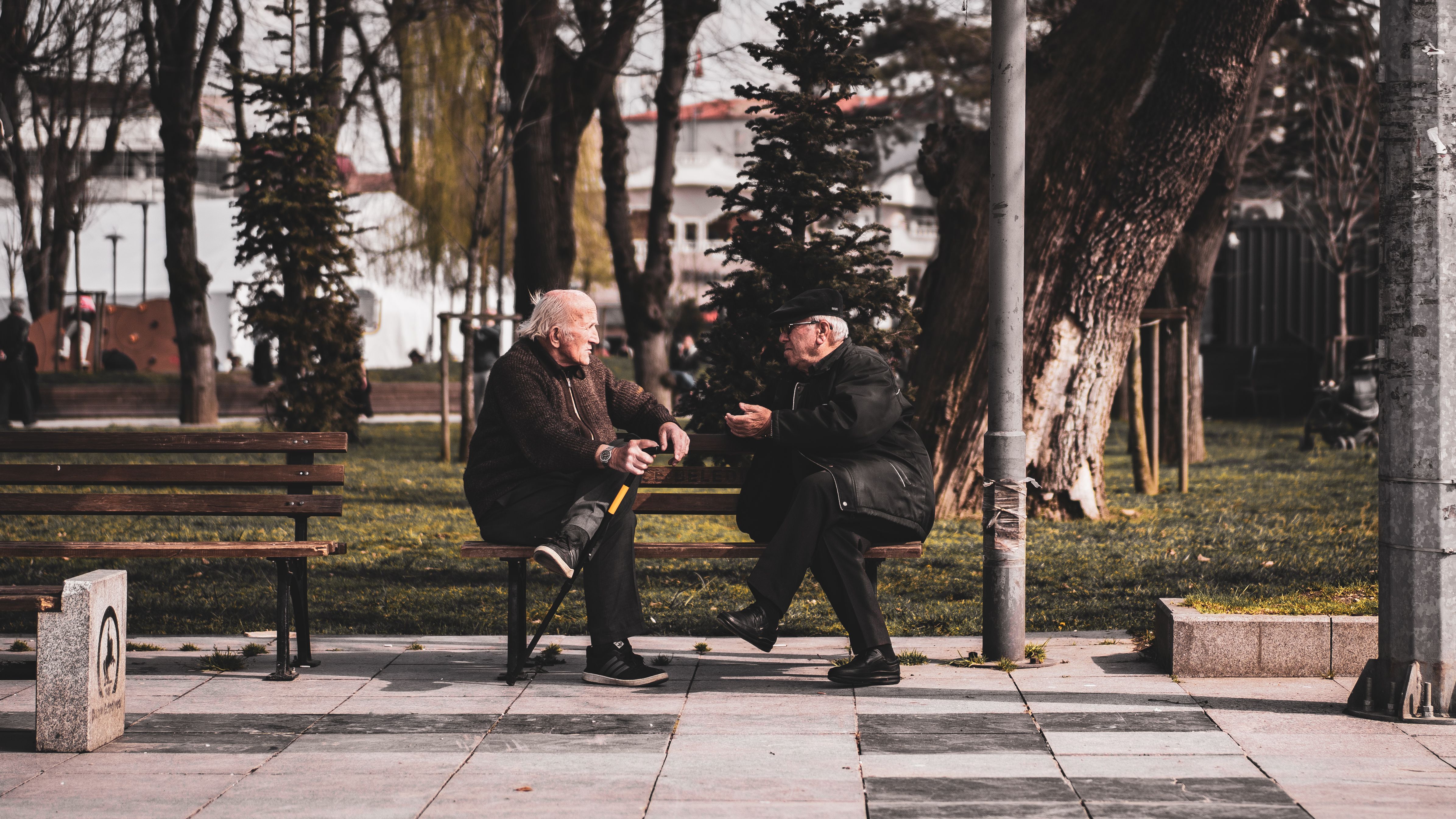 two seniors talking park bench