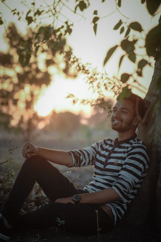A man relaxing under a tree at sunset