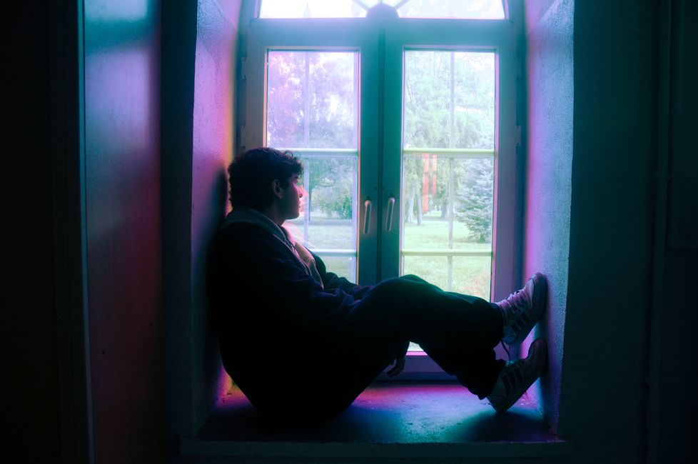 Person in silhouette sitting by a window with colored glass in Istanbul.