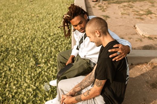 Two friends sitting together in a park, one with an arm around the other