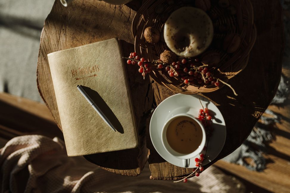 A warm, inviting scene with tea, notebook, and pastries on a rustic wooden table.