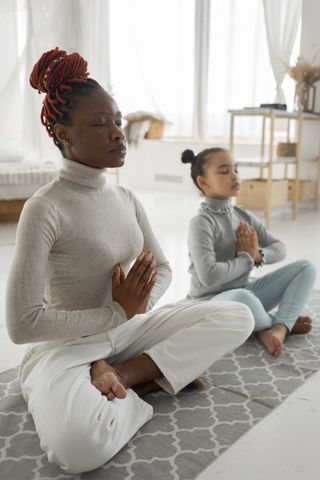 A mother and daughter meditating together at home