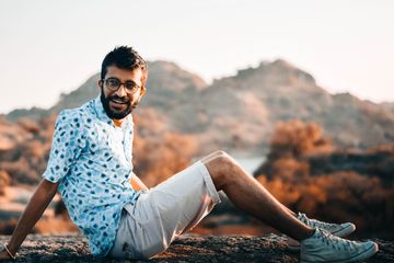 A smiling man sitting outdoors at golden hour