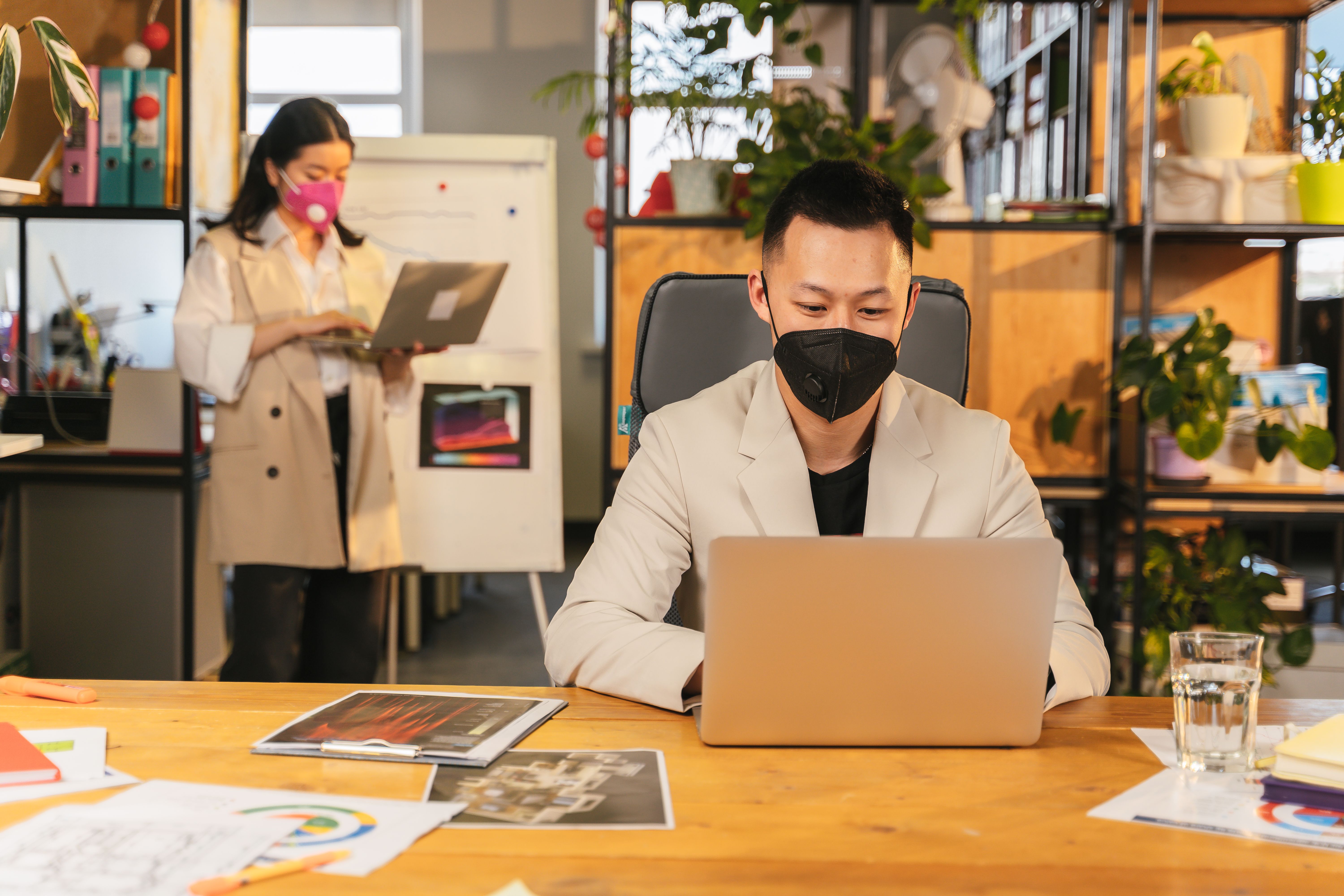 Professional team collaborating in modern office with safety measures observed, including masks.